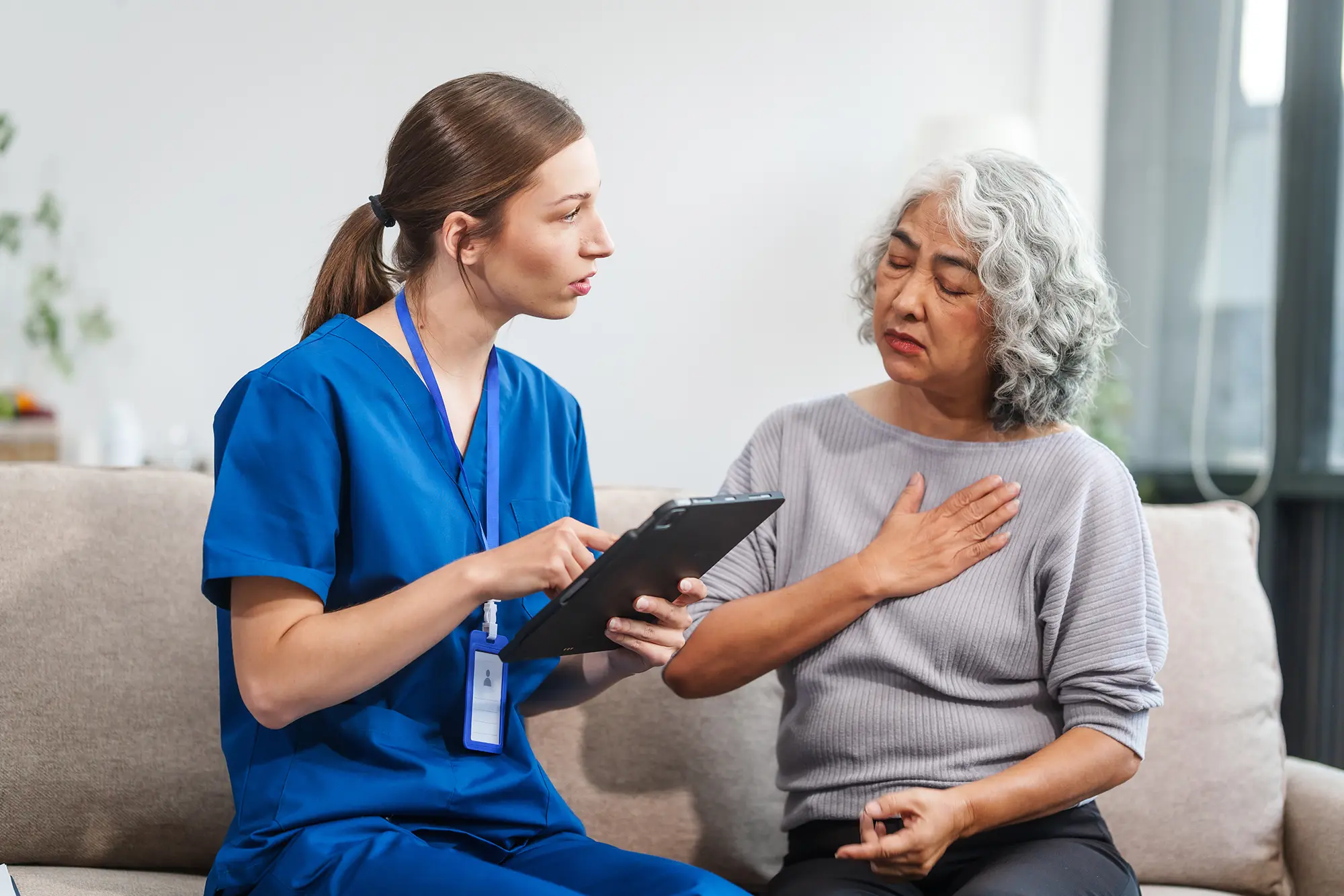 Infirmière discutant avec une patiente concernée, tablette en main.