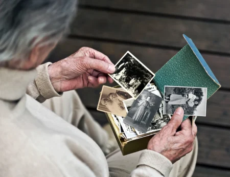 Personne âgée regarde des photos anciennes émouvantes.