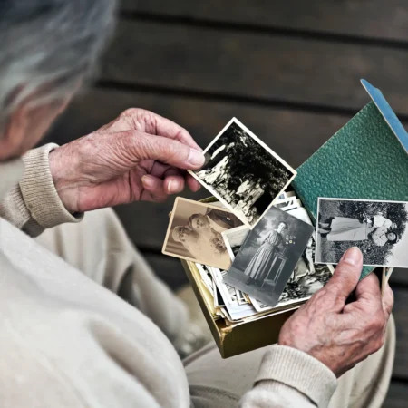 Personne âgée regarde des photos anciennes émouvantes.