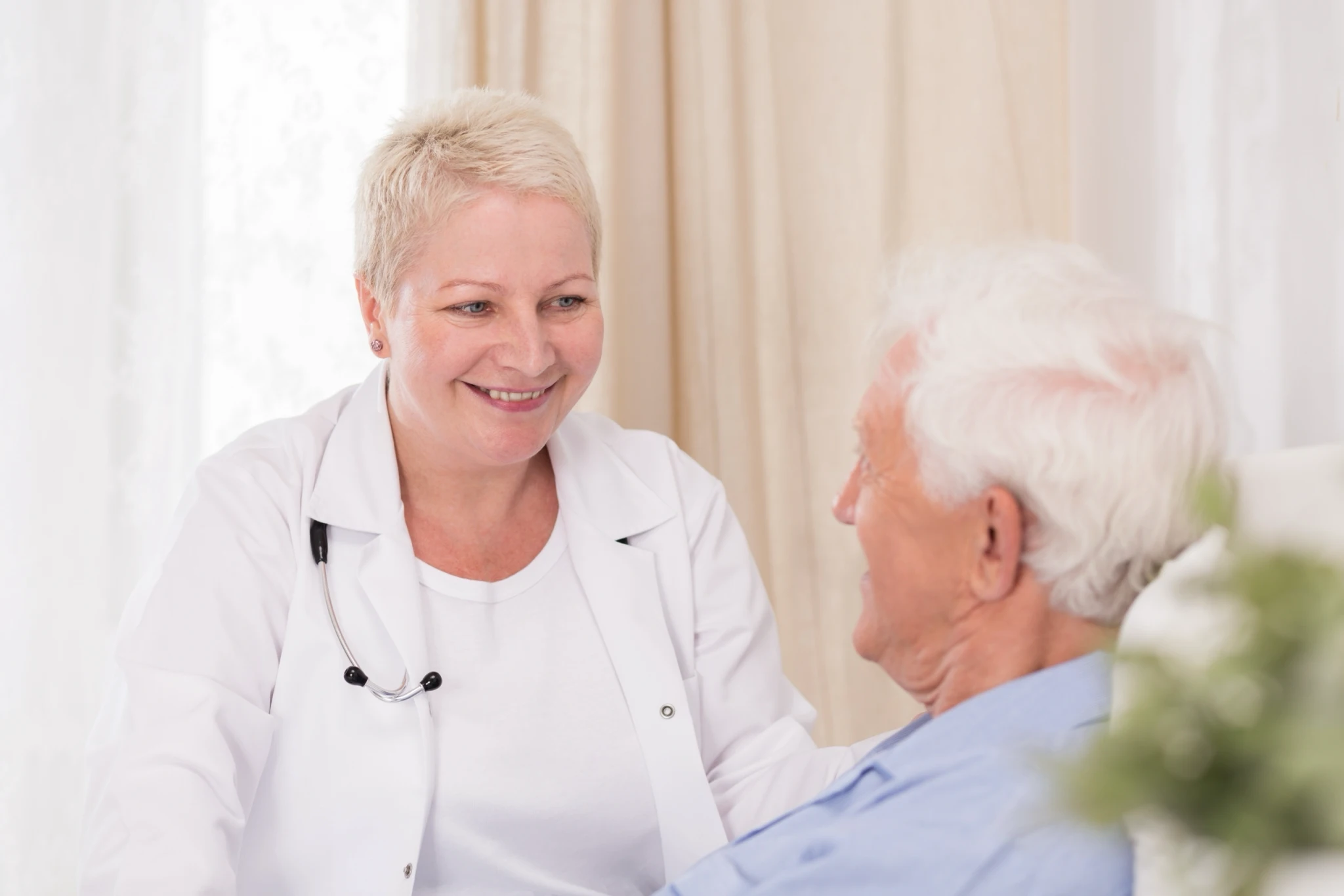 Docteure souriante avec patient âgé assis.